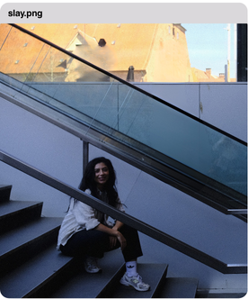 Person sitting on stairs in front of a modern glass building